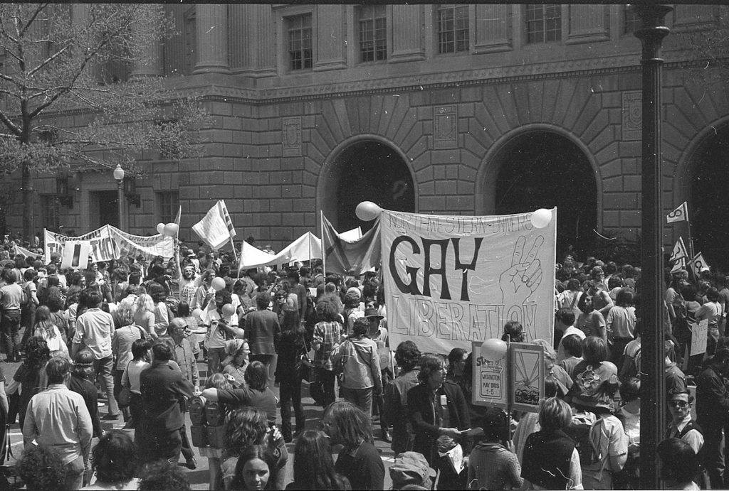 A group of pride marchers from Northwestern University hold up a sign saying "Gay Liberation"